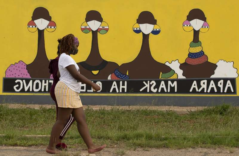a person wearing a costume a woman walks past a coronavirus themed mural promoting the use of face m 203199